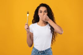 Portrait of Latin Lady Holding Fork Covering Mouth