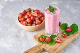 Strawberry milk shake in a glass jar and fresh strawberries with leaves